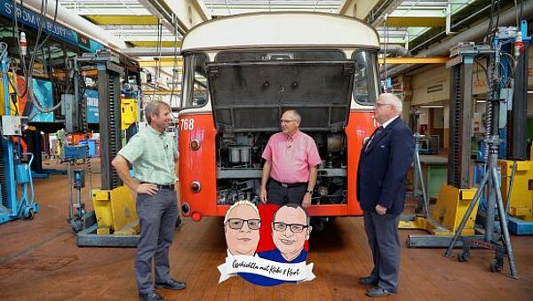 VAG-Werkstattleiter Michael Sievers, Kurt Gottschalk und Thomas Kübler vor einem Oldtimerbus in der Werkstatt