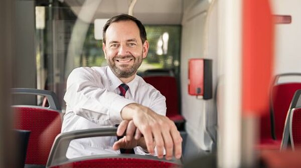 Stefan Meixner sitzt lächelnd im Fahrgastraum eines Busses