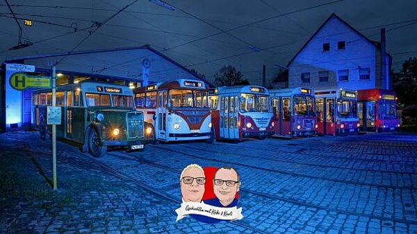 Die Oldtimerbusse aufgereiht vor dem Historischen Straßenbahndepot St. Peter, eingetaucht in blaues Licht