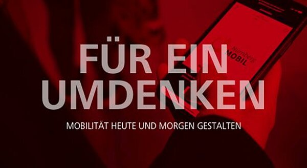 Handy mit geöffneter NürnbergMOBIL-App im Hintergrund. Davor steht "Für ein Umdenken - Mobilität heute und morgen gestalten"