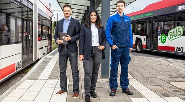 VAG-Mitarbeiter - zwei Männer und eine Frau - auf einem Bussteig und eine