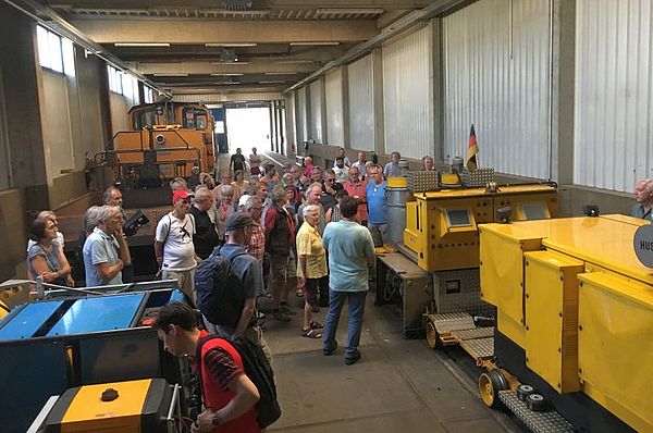 Mobile Bürgerversammlung Menschen in Wagenhalle zwischen den Arbeitsfahrzeugen.