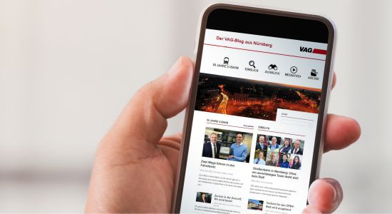 Smartphone in einer Hand haltende, darauf zu sehen der neue VAG-Blog. Smartphone in einer Hand haltende, darauf zu sehen der neue VAG-Blog.