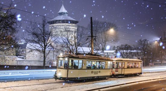 Eine Oldtimer-Straßenbahn fährt bi leichtem Schneefall den Nürnberger Burgberg hinauf