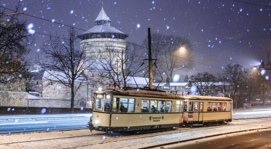 Eine Oldtimer-Straßenbahn fährt bi leichtem Schneefall den Nürnberger Burgberg hinauf