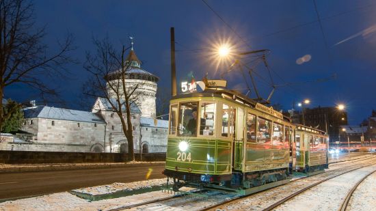 Ein Jugendstil-Zug fährt an einem verschneiten Abend entlang der Stadtmauer